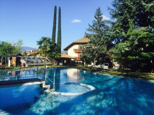 阿皮亚诺苏拉斯特拉达安格堡布鲁蒙酒店的一座拥有蓝色海水和树木的大型游泳池