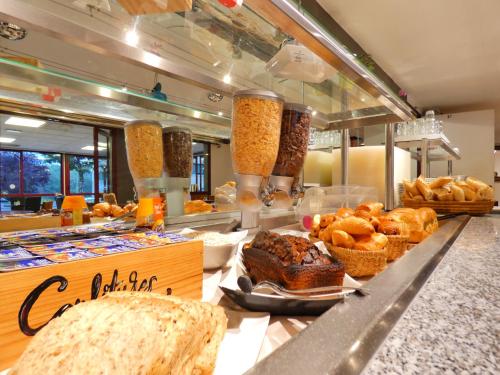 里摩日Hôtel du Parc Limoges & Restaurant "Le temps d'une pause"的面包店在柜台上供应面包和糕点