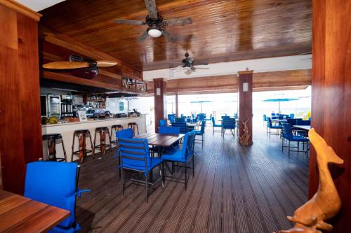 尼格瑞尔Blue Skies Beach Resort的一间配备有蓝色椅子和桌子的用餐室