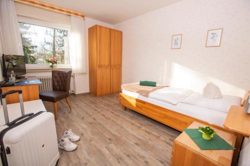 利普施塔特Hotel-Pension Haus Holtdirk的一间卧室配有一张床、一张书桌和一台电视