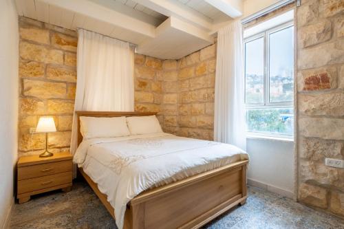 海法Via Maria Boutique Suites In The Middle Of The city的一间卧室设有一张床和石墙