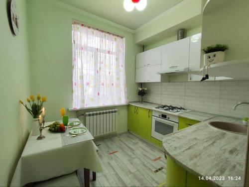 阿拉木图Стильный уют в центре的厨房设有黄色和白色的橱柜和窗户。
