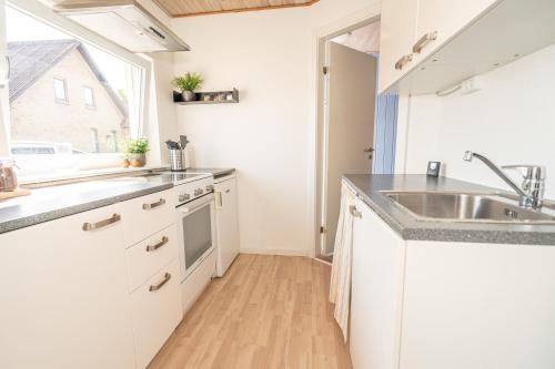 宾德斯莱弗Parkvejens feriebolig的厨房配有白色橱柜、水槽和窗户。