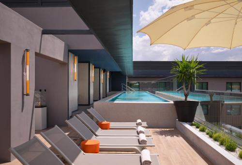 埃武拉Hilton Garden Inn Evora的游泳池旁的天井配有椅子和遮阳伞。