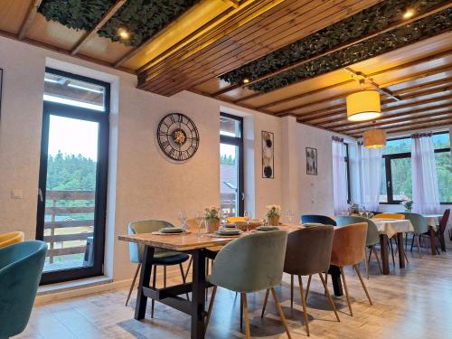 布什泰尼Vila PANORAMIC Busteni的一间设有桌椅的用餐室和墙上的时钟