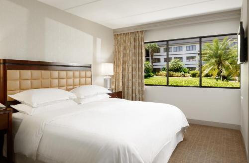 奥兰多奥兰多机场喜来登套房酒店的卧室设有一张白色大床和一扇窗户。