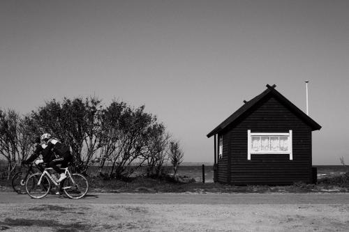 马斯塔尔Aggershøj pensionat的骑着自行车的人在小建筑旁边