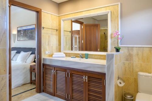 普拉亚布兰卡Hipoclub Villas, "Rosa" villa的一间带水槽和镜子的浴室以及一张床