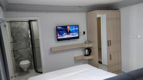 宗古尔达克TİOS OTEL的一间卧室配有一张床,墙上配有电视