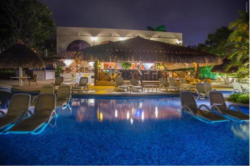普拉亚科罗纳多Private Owned Suite at Coronado Luxury Suite Hotel & Golf Course的一个带椅子的度假村,晚上有游泳池