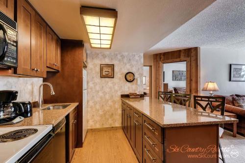 布雷肯里奇Rustic Charm Meets Comfort, Homey and Affordable with Scenic Mountain Views TE112的一间带木制橱柜的厨房和一间客厅