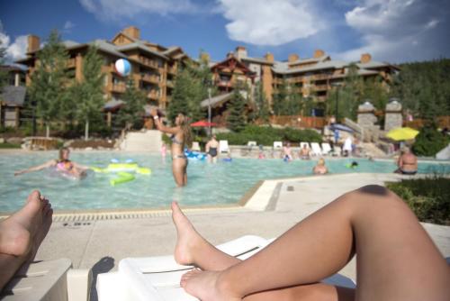 潘诺拉马全景山地度假酒店 - 滑雪/落叶松公寓的坐在游泳池椅子上的女人