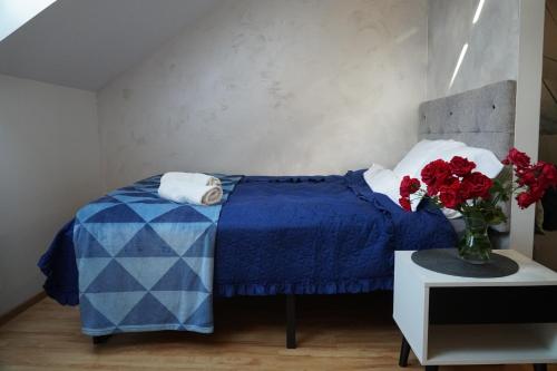 厄尔科Apartament w centrum OSTOYA 1的一间卧室配有蓝色的床和红色玫瑰花瓶