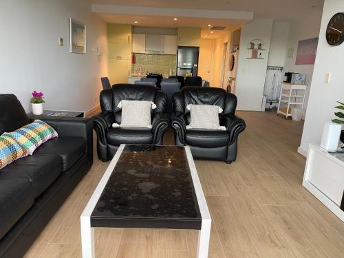 格莱内尔格Glenelg resort style beachside apartment的客厅配有黑色真皮沙发和桌子