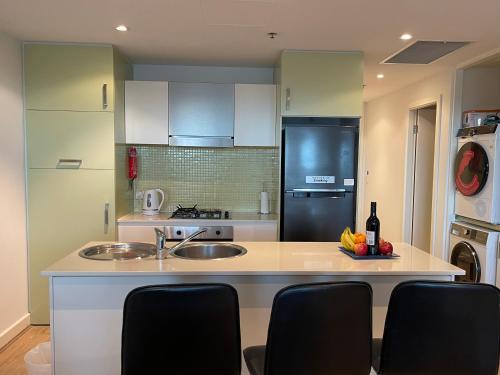 格莱内尔格Glenelg resort style beachside apartment的厨房配有水槽和带椅子的柜台。
