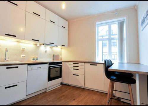 奥勒松Apartment in Ålesund city center (Storgata)的厨房配有白色橱柜、桌子和窗户。