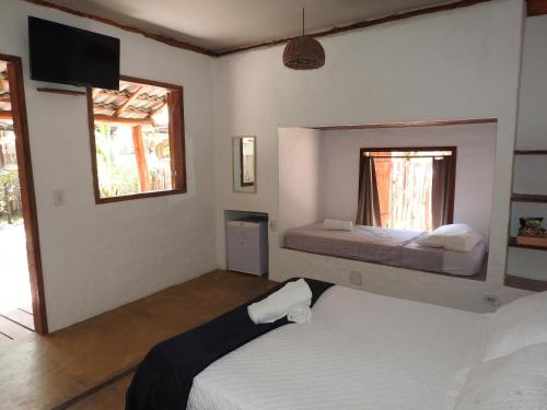 巴拉格兰德Pousada Santa Aldeia的一间卧室设有两张床,墙上配有电视。