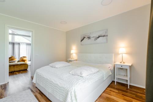 HerjavaHaagi-Villa的白色卧室配有白色的床和两盏灯。