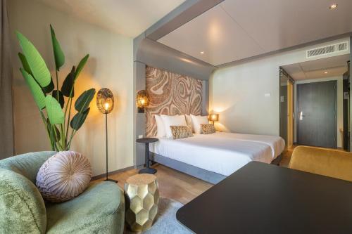 布雷达Leonardo Hotel Breda City Center的一间卧室配有一张床、一张桌子和一张沙发