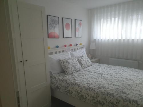 萨格勒布Cosy 35m2 appartment的一间白色的卧室,配有一张床和墙上的一些照片