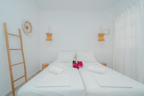 阿波罗尼亚Nostos Sifnos的白色的客房设有白色的床,床上有鲜花