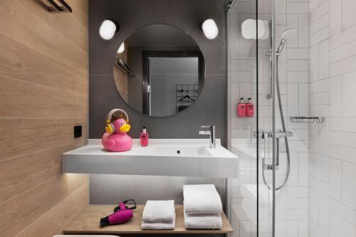 卑尔根Moxy Bergen的浴室设有水槽,而长凳上则摆放着粉红色的鸭子。
