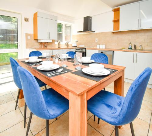 米尔顿凯恩斯Milton Keynes Modern City House的厨房配有木桌和蓝色椅子
