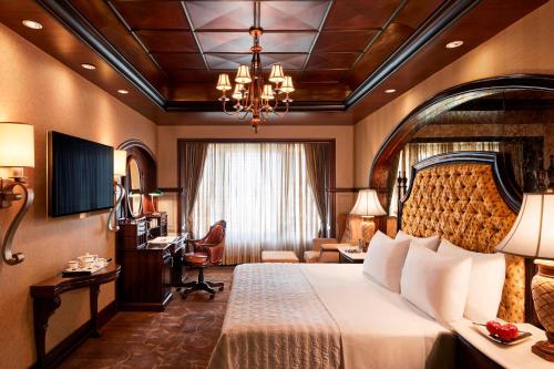 新德里新德里艾美酒店 的酒店客房设有一张大床和一张书桌。