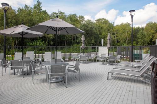 奥兰多TownePlace Suites by Marriott Orlando Airport的一个带桌椅和遮阳伞的庭院