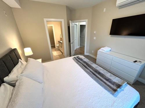 West KelownaStay In The Okanagan - Copper Sky, West Kelowna的卧室配有白色的床和平面电视。
