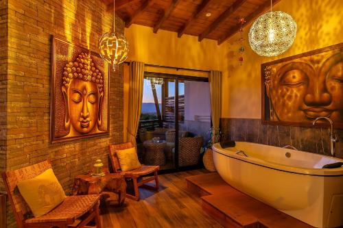 普腊亚罗萨Shiva Boutique Hotel - Praia do Rosa的浴室配有浴缸和墙上的2面罩
