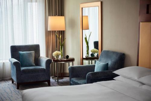 武汉武汉光明万丽酒店的酒店客房带两把椅子、一张床和镜子