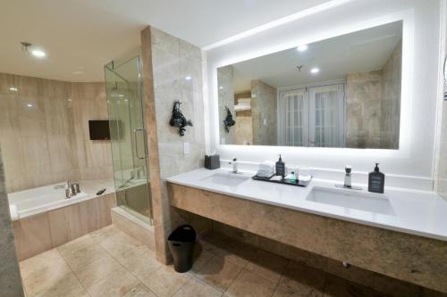 拉瓦尔拉瓦尔喜来登酒店 的浴室设有2个盥洗盆、淋浴和镜子。