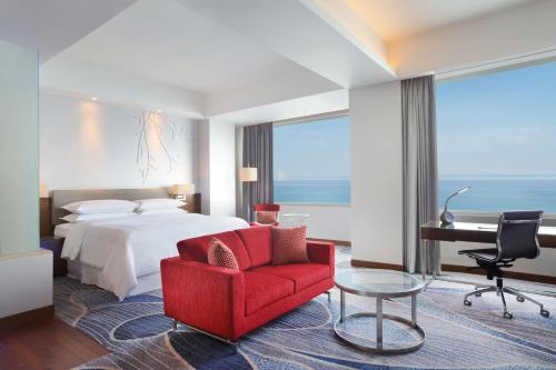 美娜多万鸦老福朋喜来登酒店的酒店客房配有一张床、一张红色椅子和一张书桌