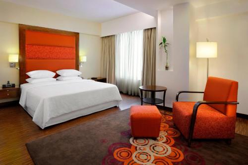 艾哈迈达巴德艾哈迈达巴德福朋喜来登酒店的配有一张床和一把椅子的酒店客房