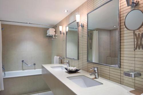 吉布提吉布提喜来登酒店的浴室设有2个水槽、镜子和浴缸。