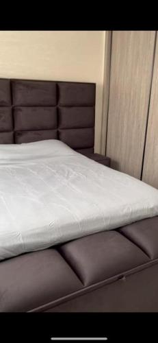 纳祖尔Appartement Nador Jadid的一张铺有白色床单的床和一张棕色床头板