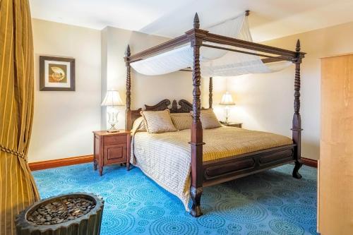 鲸湾港鹈鹕湾普罗提酒店 的一间卧室配有天蓬床和蓝色地毯