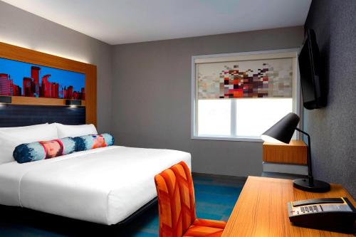 卡尔加里Aloft Hotel Calgary University的一间卧室配有一张床、一张桌子和一个窗户。