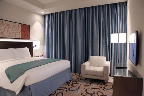 麦地那Marriott Executive Apartments Madinah的配有一张床和一把椅子的酒店客房