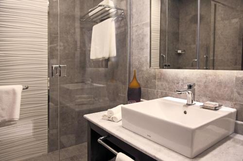 麦地那Marriott Executive Apartments Madinah的一间带水槽、镜子和淋浴的浴室