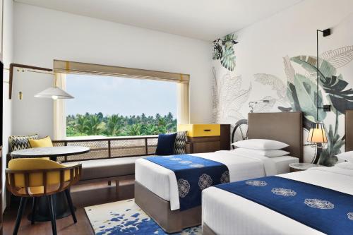 尼杜巴塞莱Port Muziris, A Tribute Portfolio Hotel的酒店客房设有两张床和窗户。