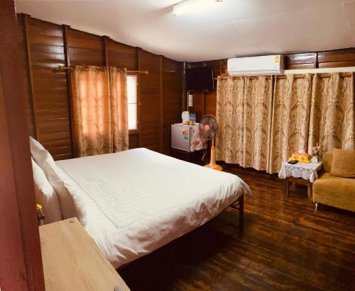 佛丕Banthai Guesthouse的一间卧室,卧室内配有一张床和一把椅子