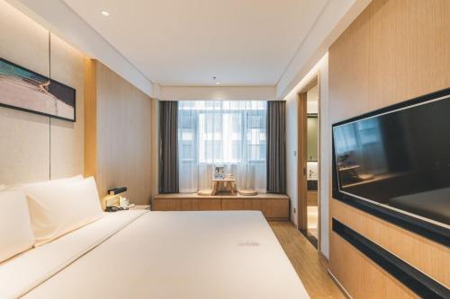 无锡无锡东亭博乐诗亚朵酒店的一间卧室配有一张床和一台平面电视
