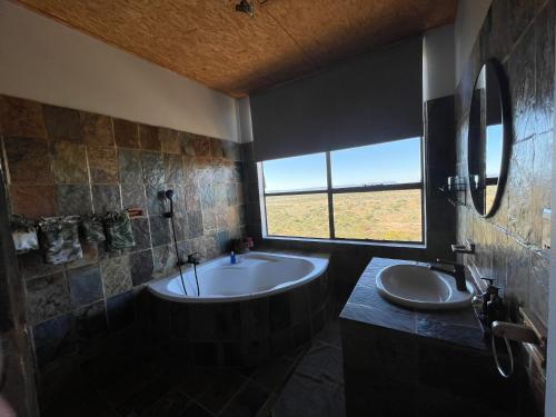 奥奇瓦龙戈Aloegrove Safari Lodge的带浴缸、两个盥洗盆和窗户的浴室