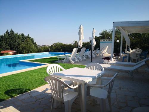 图里莉娜别墅住宿加早餐旅馆的一个带白色桌椅的庭院,毗邻游泳池
