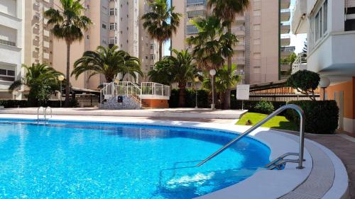 甘迪亚Caballito de mar, parking, AC y fibra VT-52619-V的一座种植了棕榈树和建筑的大型蓝色游泳池