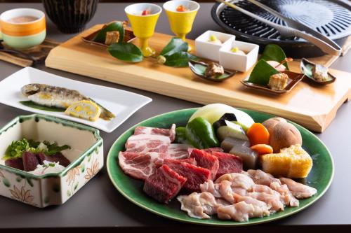 南小国町Hanare no Yado Hanagokoro的一张桌子,上面放着一盘肉和其他食物