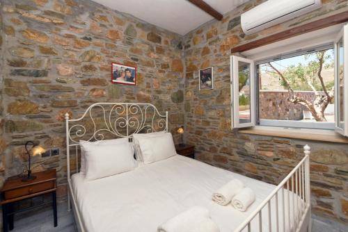 LiaropáFlora's beach and pool villa in Syros的卧室配有白色的床铺和石墙