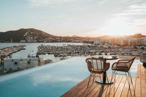 圣埃乌拉利亚Aguas de Ibiza Grand Luxe Hotel - Small Luxury Hotel of the World的一个带椅子的屋顶游泳池,享有海港的景色